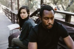 A couple in a serious moment, suggesting conflict or breakup, outdoors.