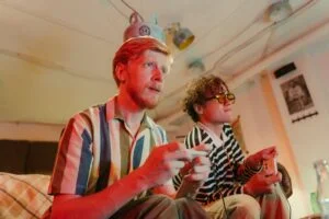 Two men playing video games with controllers and having fun in a cozy room.